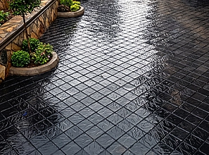 A worker installing concrete floor tiles or pavers by hand during an outdoor paving and construction process